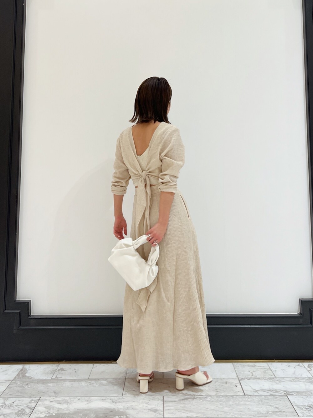 ホワイト系のベスト、ホワイト系のワンピース、ホワイト系のハンドバッグを着用したレディースの春コーディネートの1枚目の写真