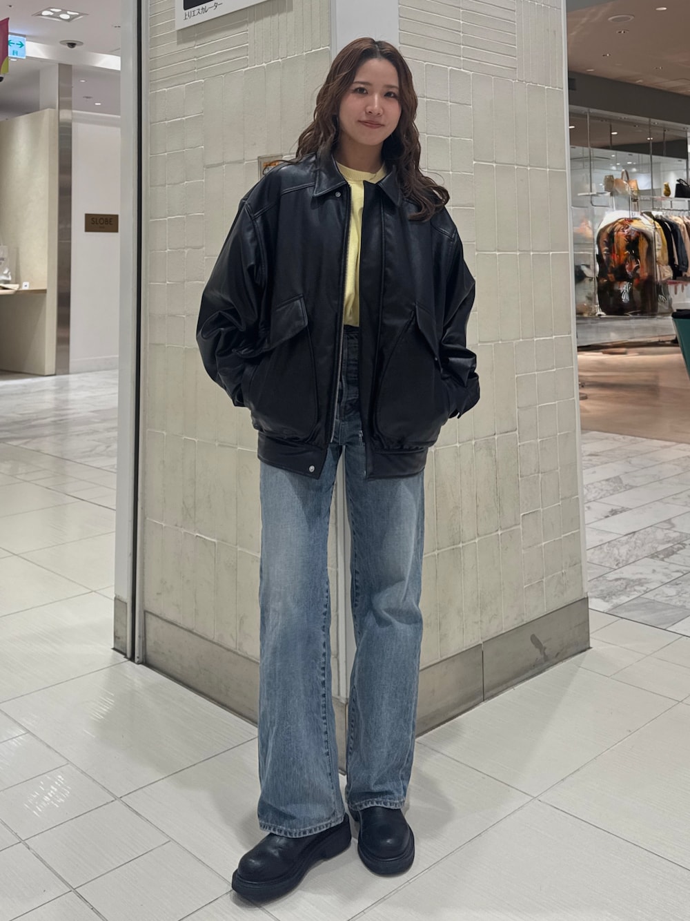 ブルー系のデニムパンツ、ブラック系のブルゾン、イエロー系のニット/セーターを着用したレディースの冬コーディネートの1枚目の写真