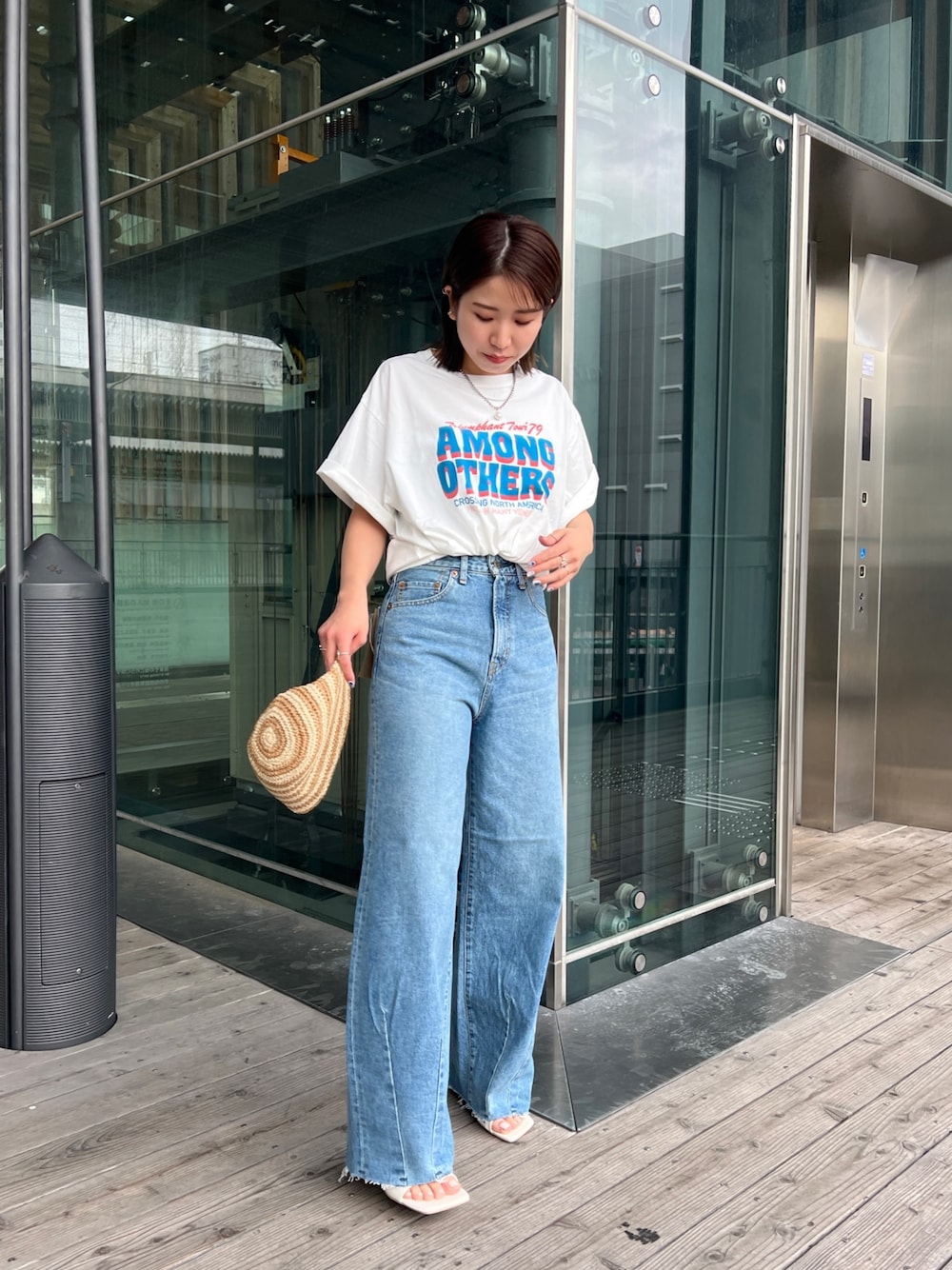 ホワイト系のTシャツ/カットソー、ホワイト系のサンダル、ブルー系のデニムパンツを着用したレディースの春コーディネートの1枚目の写真