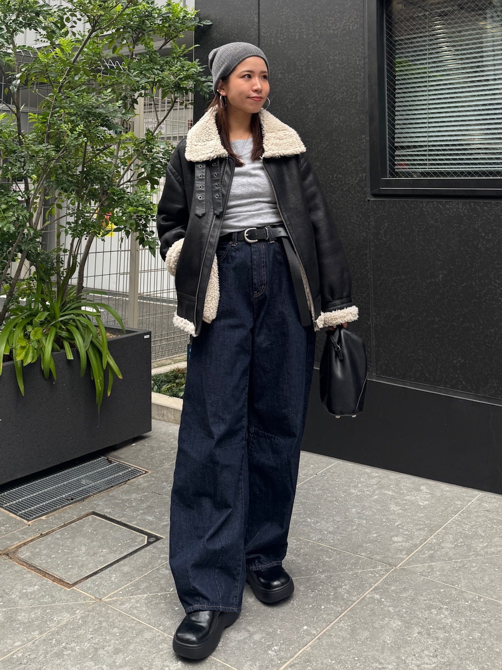 ブラック系のブルゾン、ブルー系のデニムパンツ、グレー系のニット/セーターを着用したレディースの秋コーディネートの1枚目の写真