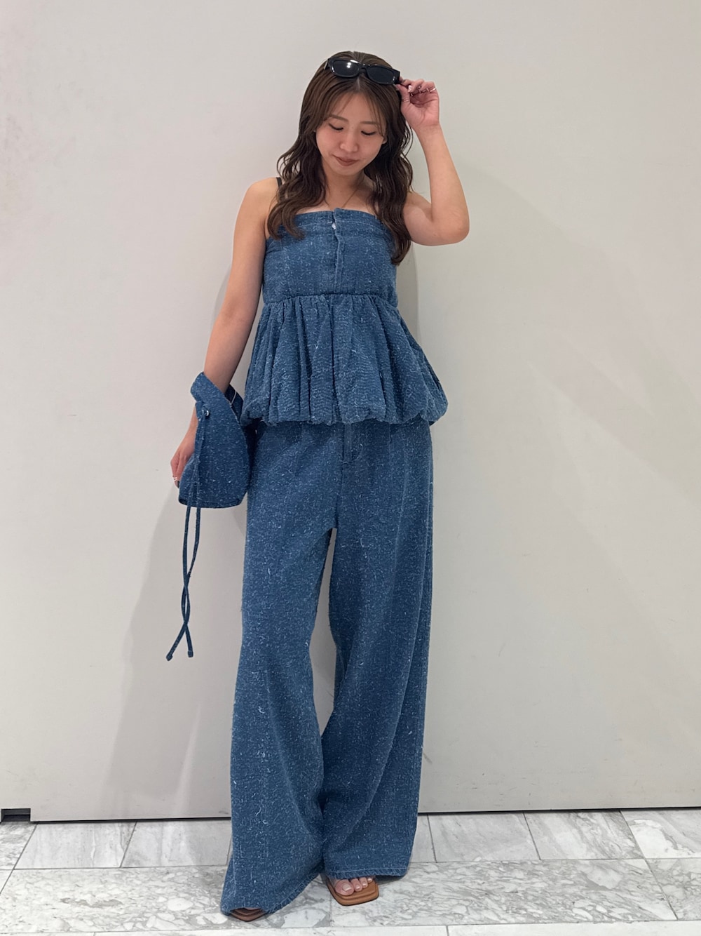 ブルー系のチューブトップ、ブルー系のデニムパンツ、ブルー系のハンドバッグを着用したレディースの春コーディネートの1枚目の写真
