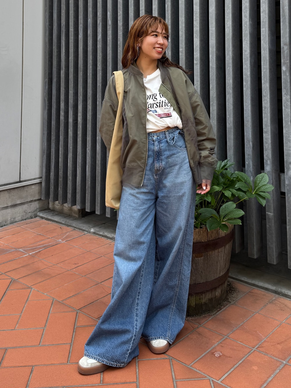 ベージュ系のトートバッグ、ホワイト系のタンクトップ、ブルー系のデニムパンツを着用したレディースの夏コーディネートの1枚目の写真