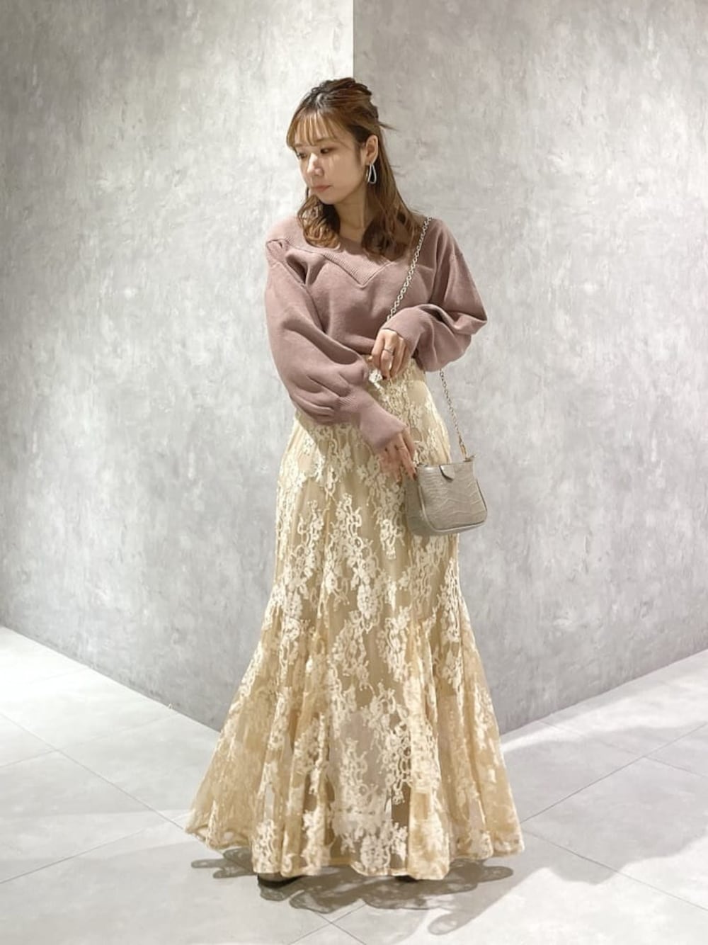 ピンク系のニット/セーター、ベージュ系のスカート、ベージュ系のスカートを着用したレディースの秋コーディネートの1枚目の写真