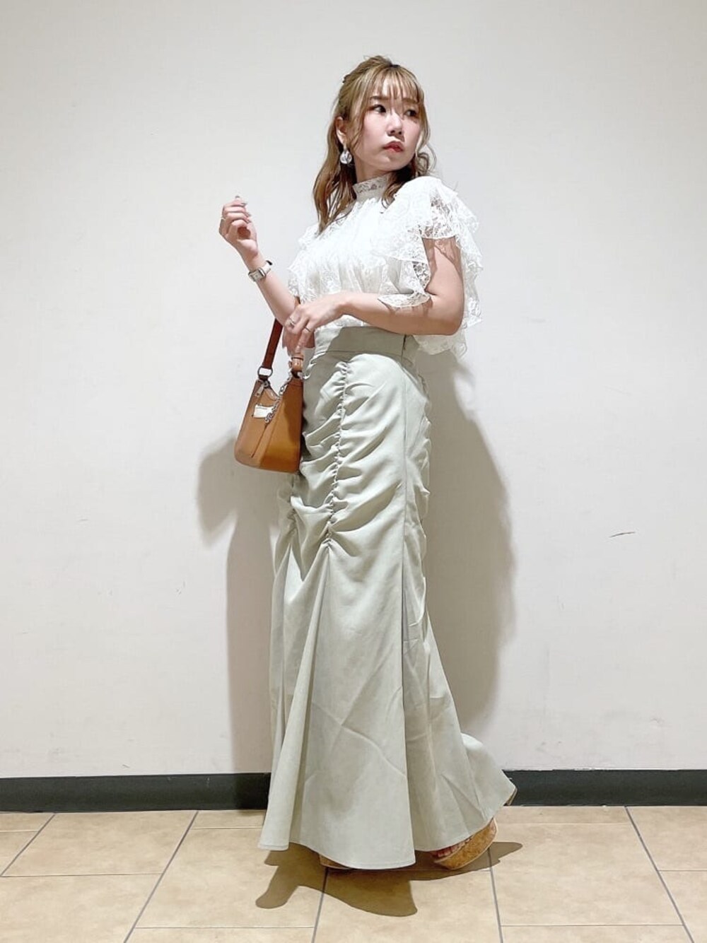 グリーン系のスカート、ブラウン系のハンドバッグ、ホワイト系のシャツ/ブラウスを着用したレディースの夏コーディネートの1枚目の写真