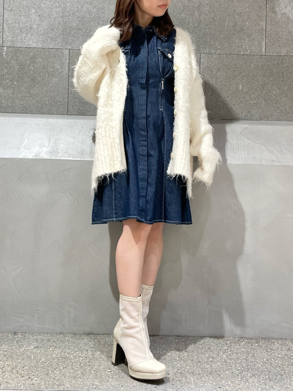 ホワイト系のカーディガン/ボレロ、ブルー系のシャツワンピース、ホワイト系のブーツを着用したレディースの冬コーディネートの1枚目の写真