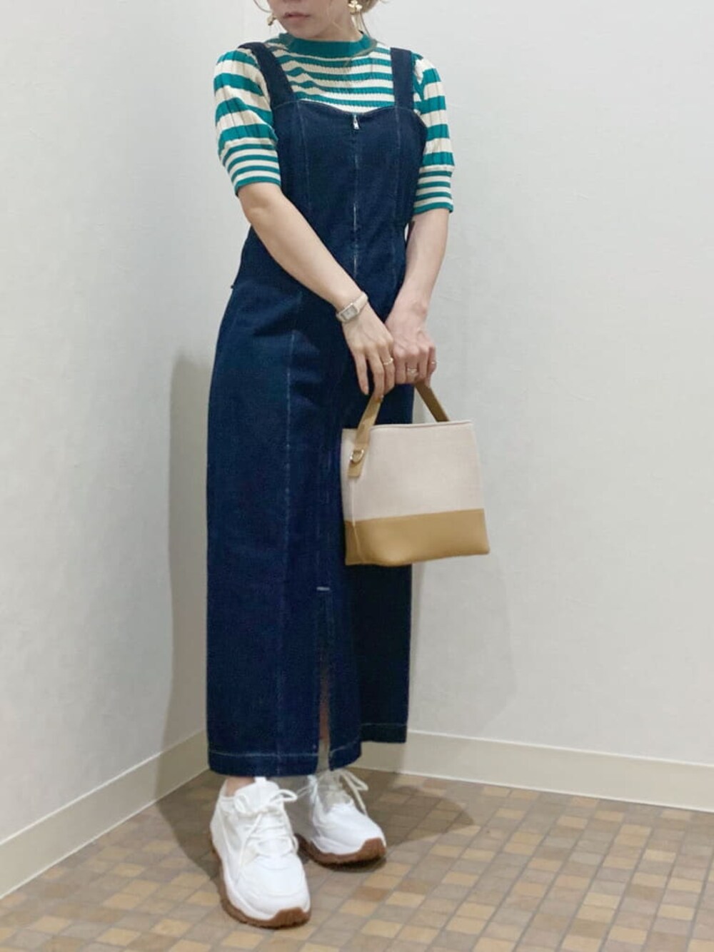 ホワイト系のスニーカー、ブルー系のジャンパースカート、グリーン系のニット/セーターを着用したレディースの春コーディネートの1枚目の写真