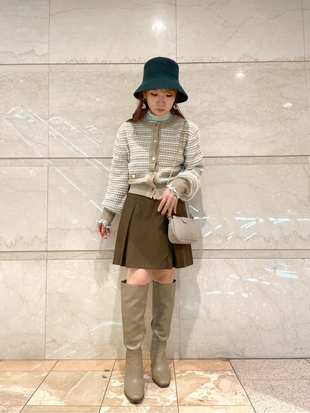 ブラウン系のスカート、ベージュ系のブーツ、ベージュ系のカーディガン/ボレロを着用したレディースの秋コーディネートの1枚目の写真