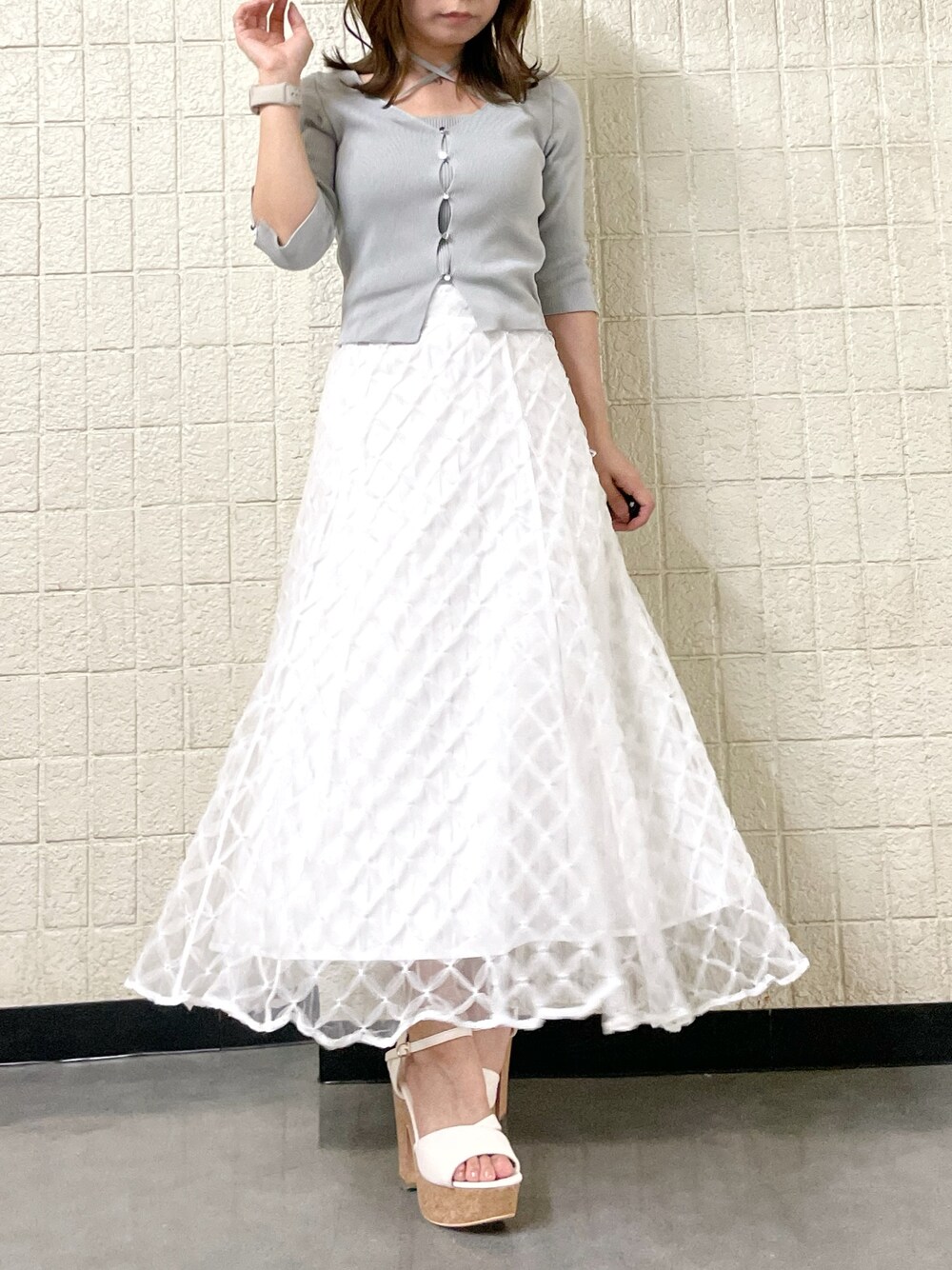 グレー系のニット/セーター、ホワイト系のスカート、ホワイト系のサンダルを着用したレディースの春コーディネートの1枚目の写真