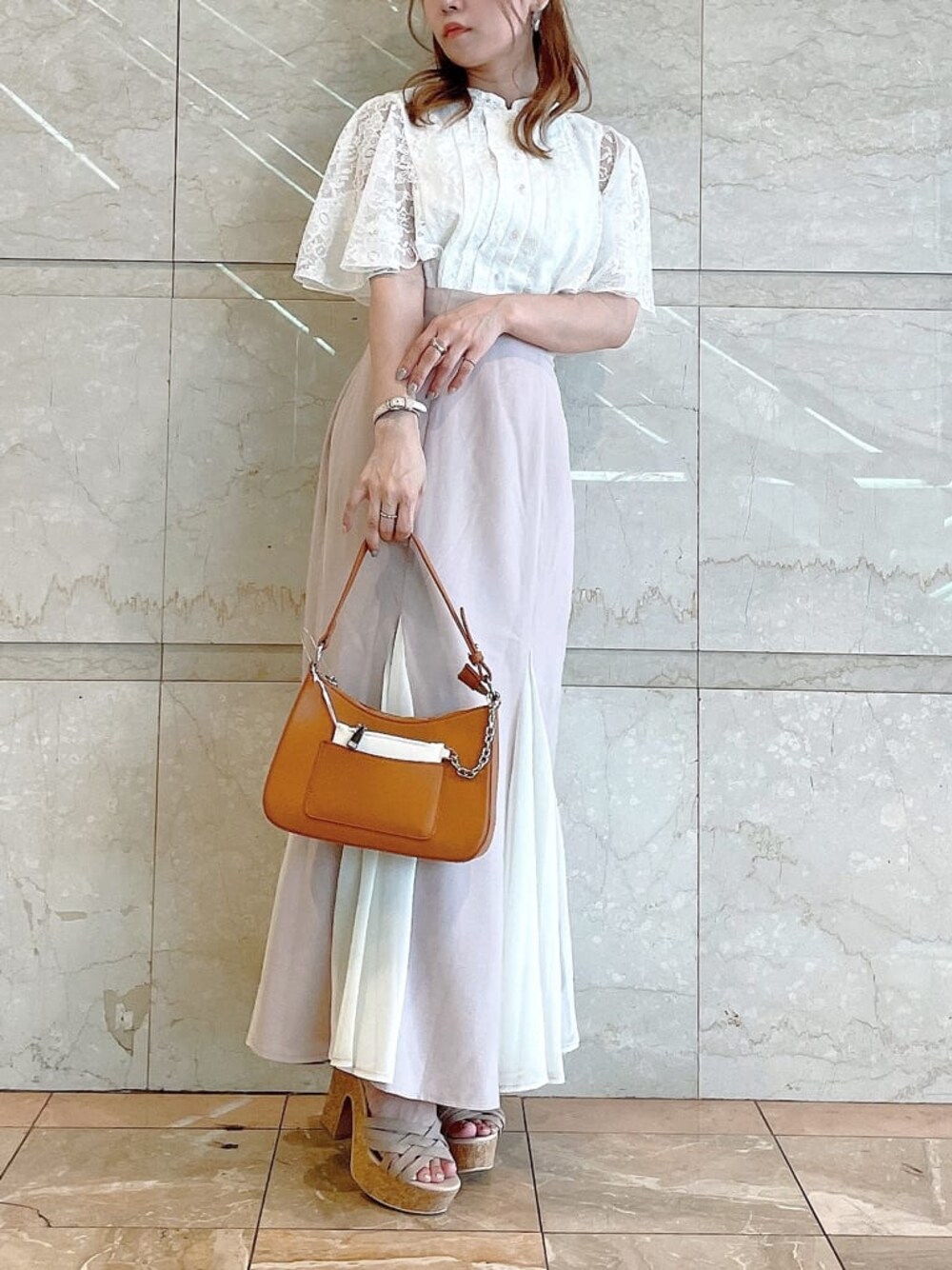 ブラウン系のハンドバッグ、ホワイト系のシャツ/ブラウス、ベージュ系のサンダルを着用したレディースの夏コーディネートの1枚目の写真