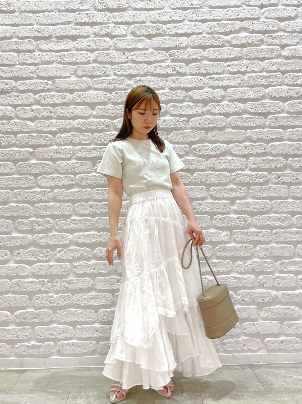 グリーン系のTシャツ/カットソー、ホワイト系のスカート、シルバー系のパンプスを着用したレディースの春コーディネートの1枚目の写真