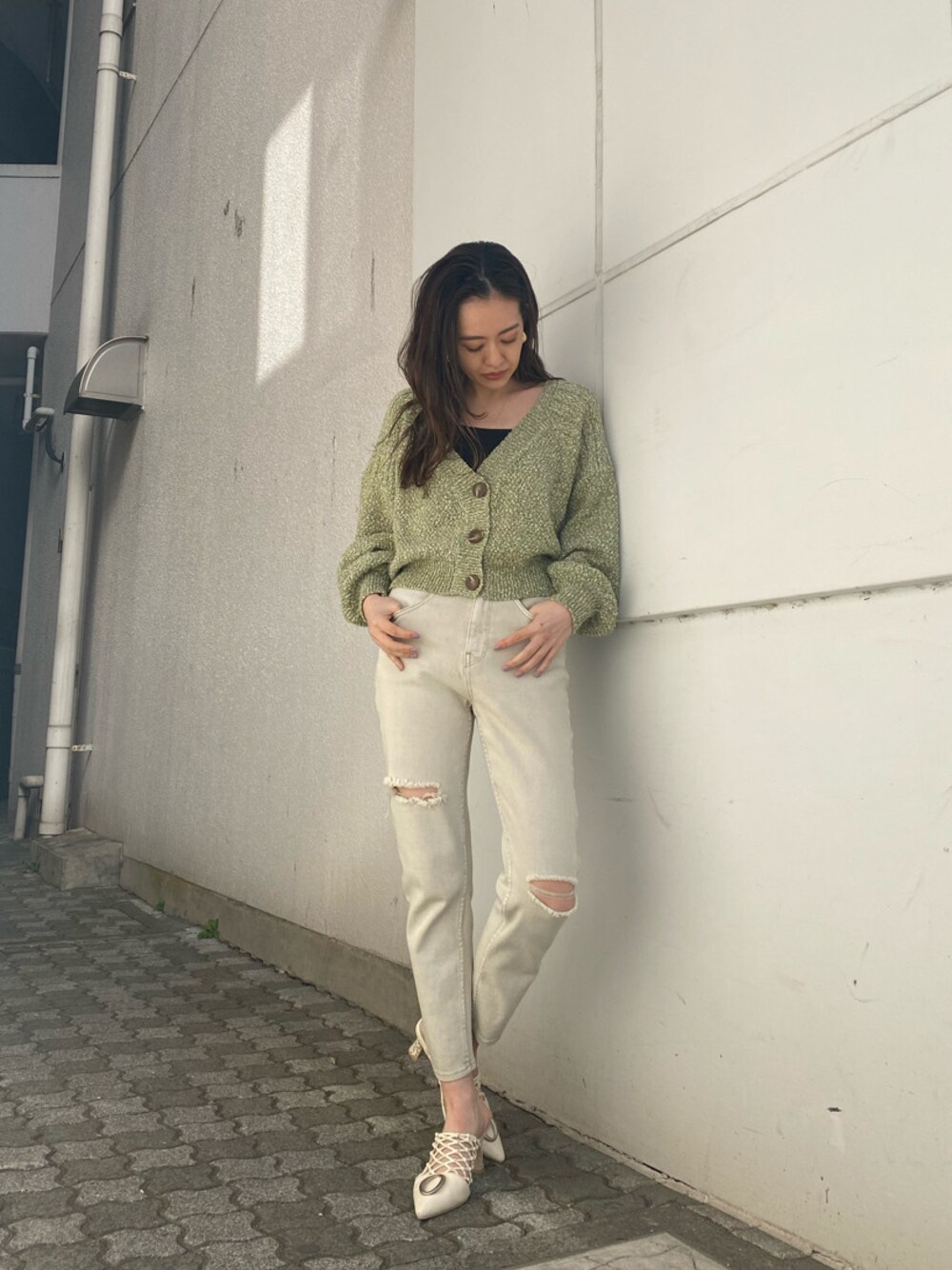 グリーン系のカーディガン/ボレロ、ホワイト系のパンプス、ゴールド系のイヤリングを着用したレディースの冬コーディネートの1枚目の写真