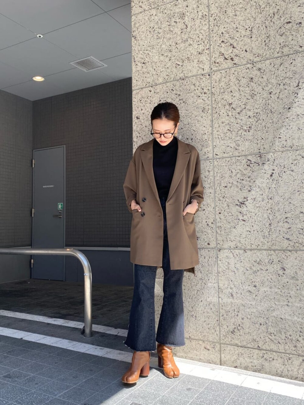 ベージュ系のテーラードジャケット、ブラック系のニット/セーター、ブラック系のデニムパンツを着用したレディースの秋コーディネートの1枚目の写真