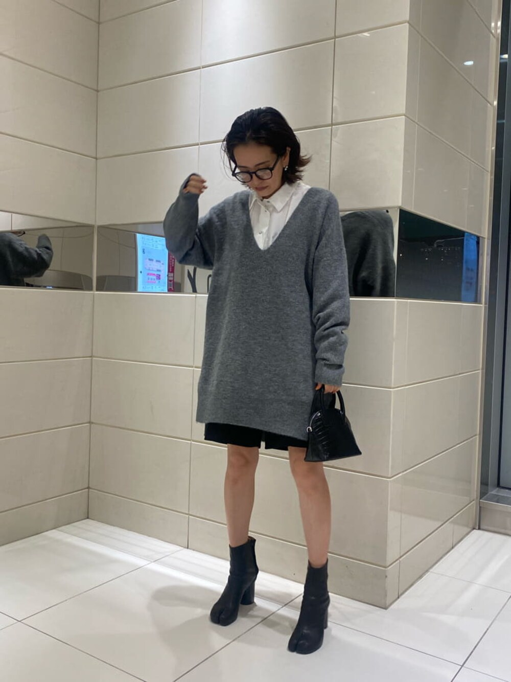 ブラック系のハンドバッグ、グレー系のニット/セーターを着用したレディースの秋コーディネートの1枚目の写真