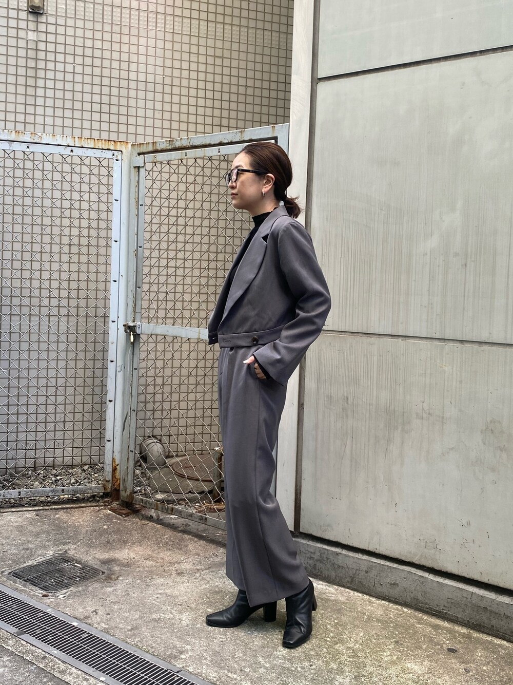 グレー系のテーラードジャケット、ブラック系のニット/セーター、グレー系のスラックスを着用したレディースの冬コーディネートの1枚目の写真