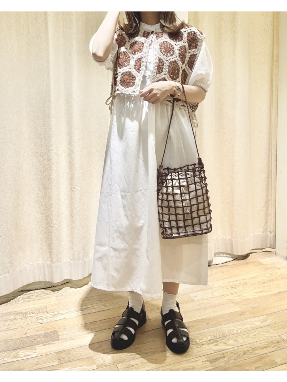 ブラウン系のベスト、ホワイト系のワンピース、ブラウン系のサンダルを着用したレディースの夏コーディネートの1枚目の写真