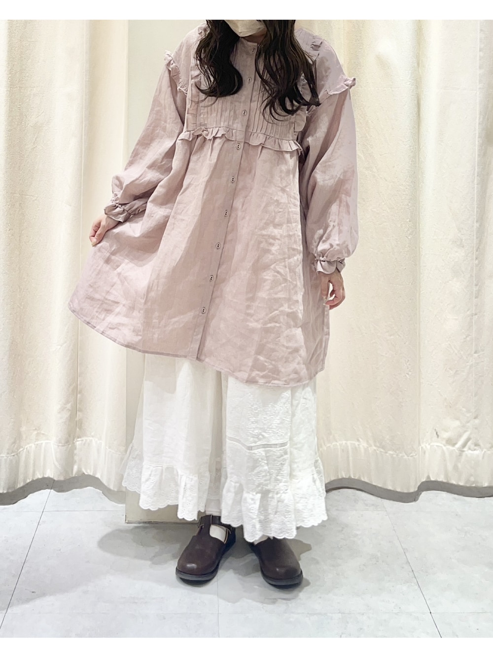 ピンク系のチュニック、ホワイト系のスカート、ブラウン系のドレスシューズを着用したレディースの秋コーディネートの1枚目の写真
