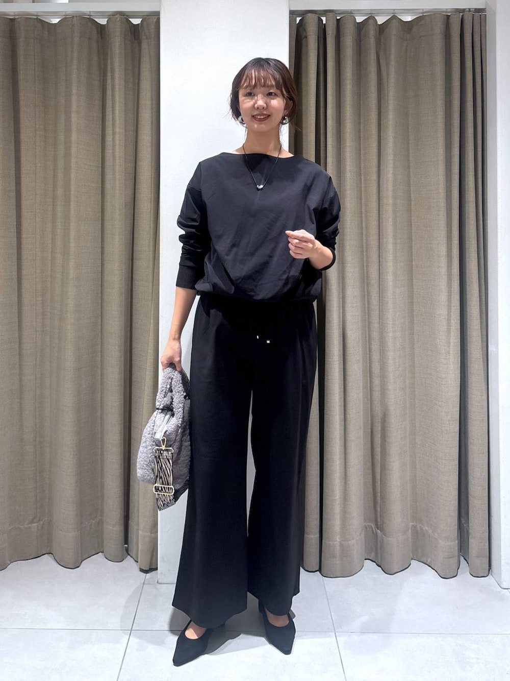 ブラック系のパンプス、グレー系のトートバッグ、ブラック系のTシャツ/カットソーを着用したレディースの秋コーディネートの1枚目の写真