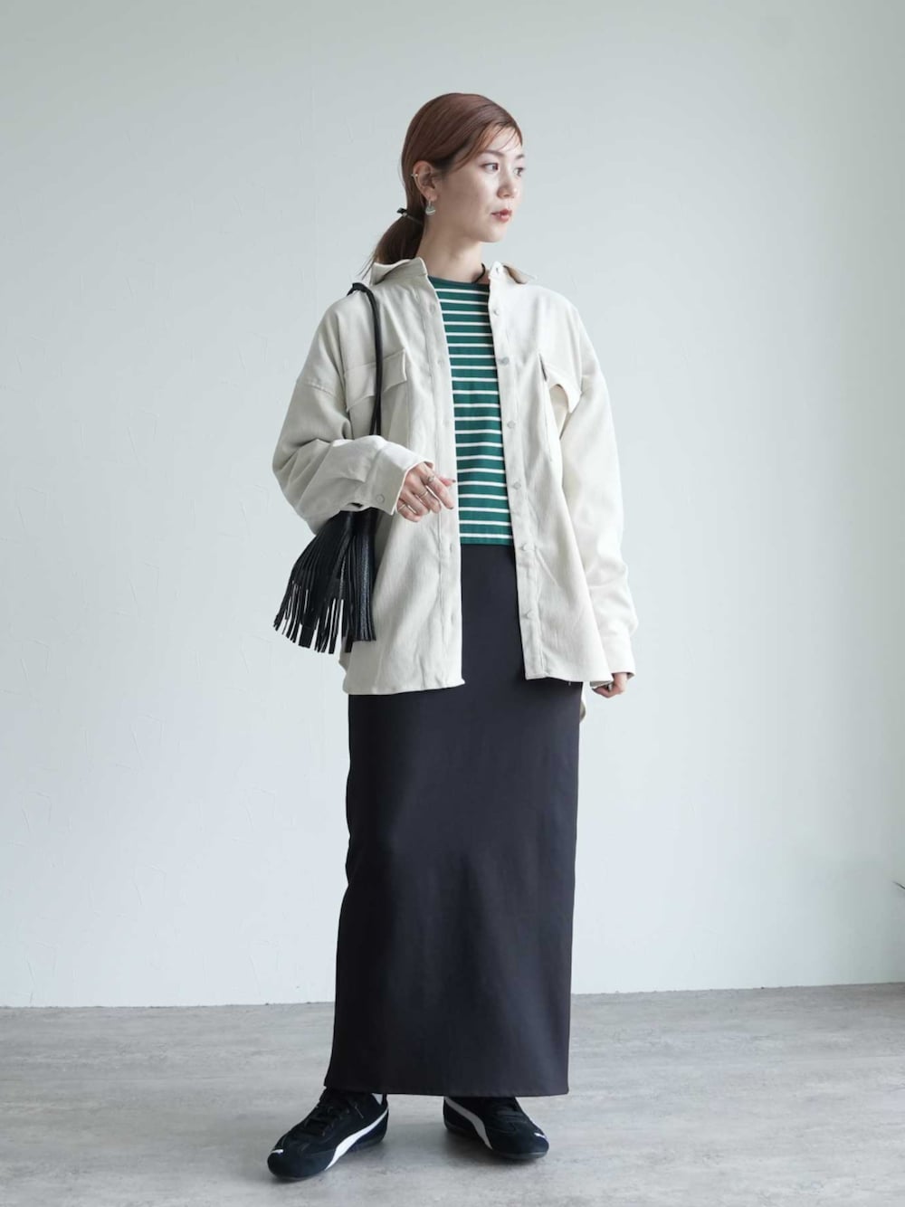 ブラック系のスカート、グリーン系のTシャツ/カットソー、ホワイト系のシャツ/ブラウスを着用したレディースの秋コーディネートの1枚目の写真