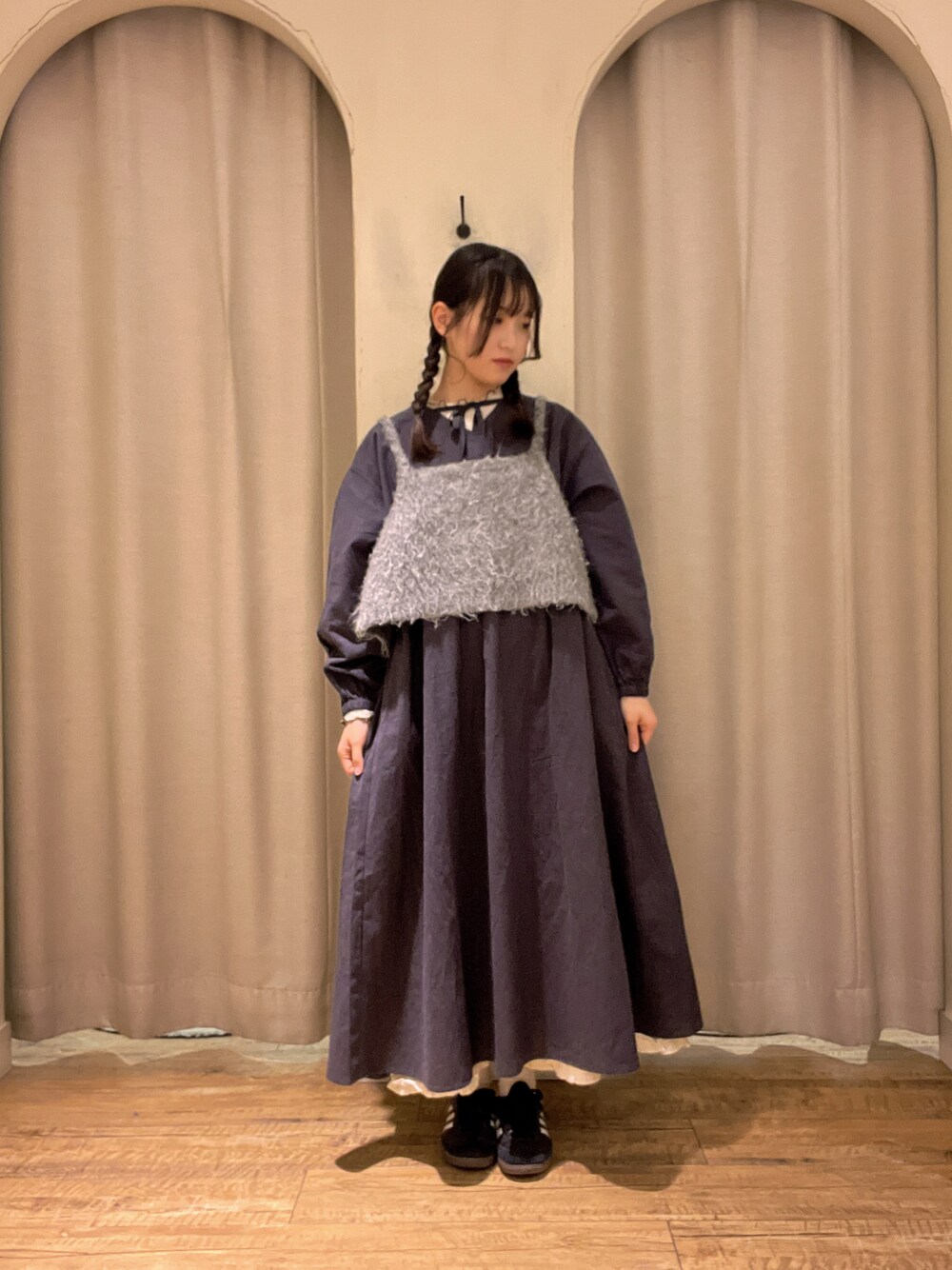 グレー系のベスト、ブラック系のワンピース、ホワイト系のTシャツ/カットソーを着用したレディースの冬コーディネートの1枚目の写真