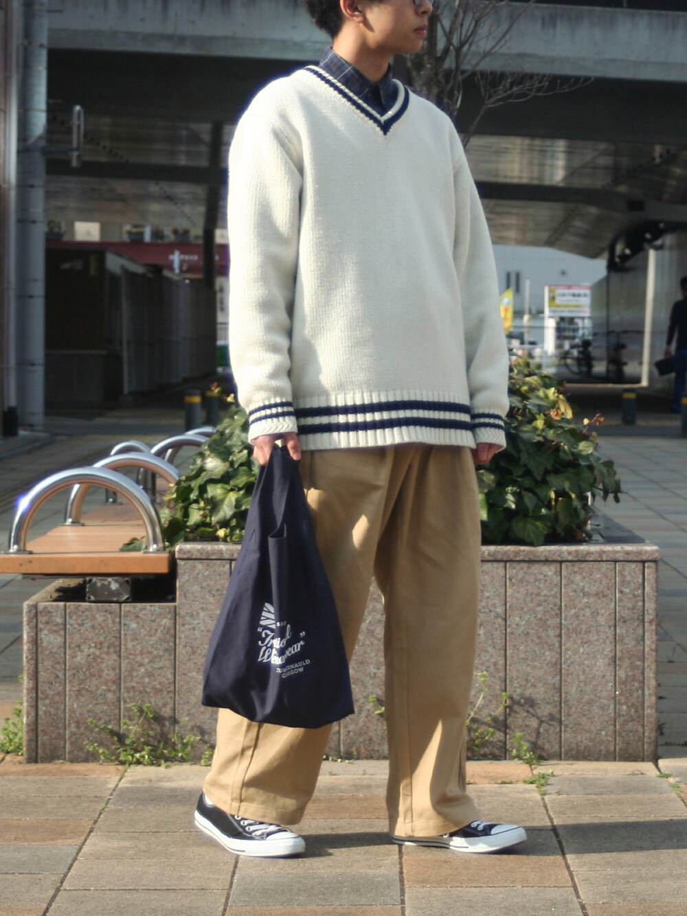 ホワイト系のニット/セーター、ベージュ系のチノパンツ、ブラック系のスニーカーを着用したメンズの春コーディネートの1枚目の写真