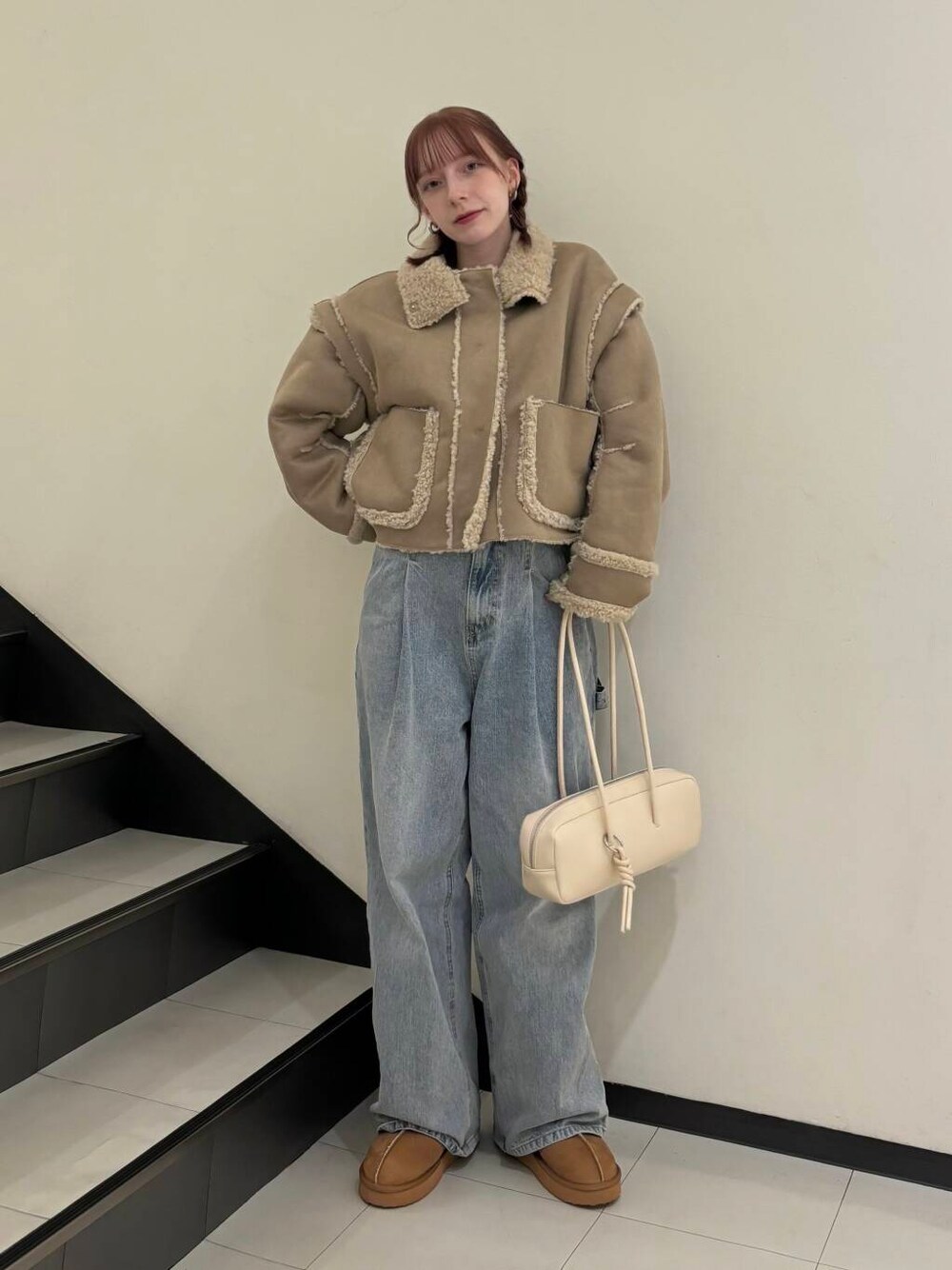 ブルー系のデニムパンツ、ベージュ系のその他アウター、ホワイト系のショルダーバッグを着用したレディースの秋コーディネートの1枚目の写真