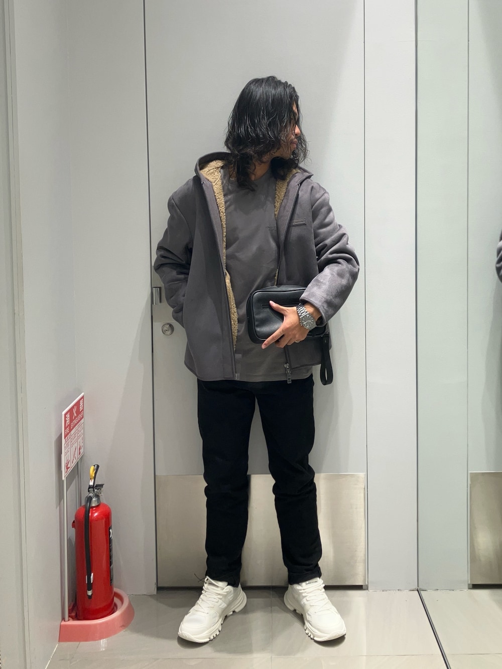 ホワイト系のスニーカー、ブラック系のデニムパンツ、グレー系のムートンコートを着用したメンズの冬コーディネートの1枚目の写真