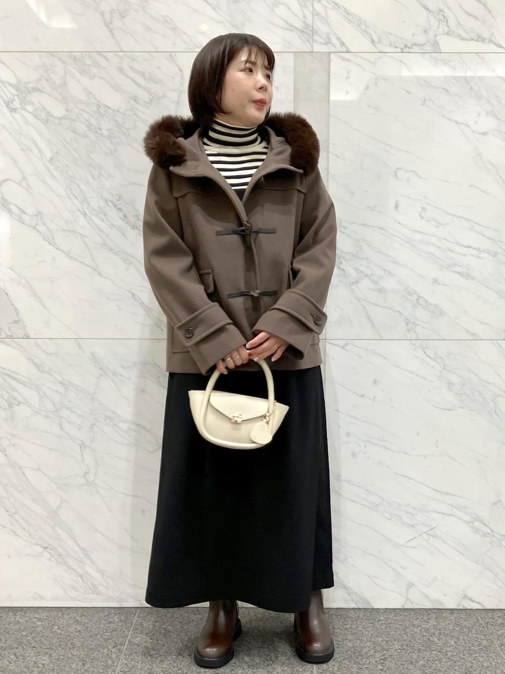 ブラック系のワンピース、ブラウン系のダッフルコート、ホワイト系のニット/セーターを着用したレディースの冬コーディネートの1枚目の写真