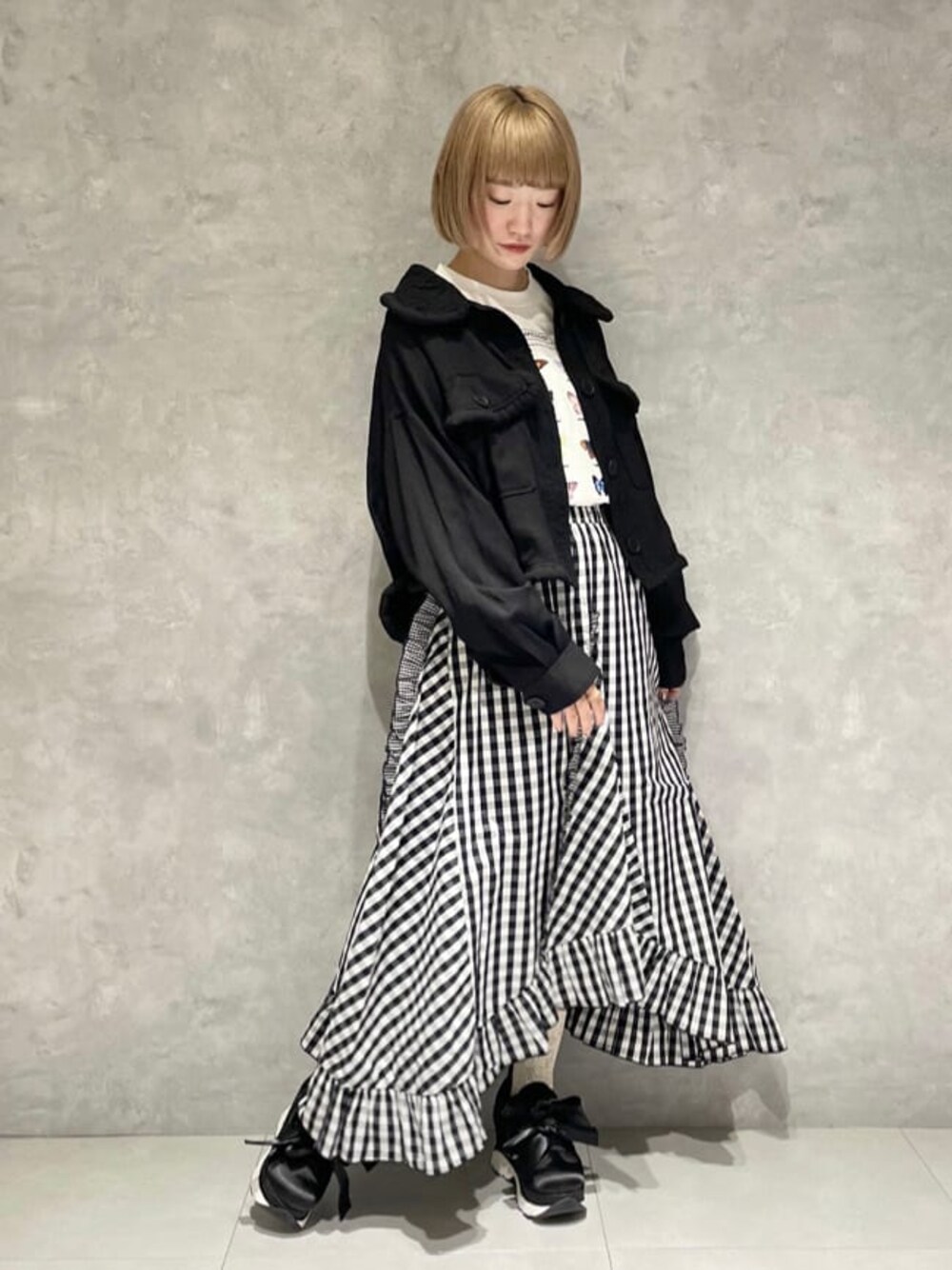 ブラック系のテーラードジャケット、ホワイト系のTシャツ/カットソー、ブラック系のスカートを着用したレディースの秋コーディネートの1枚目の写真