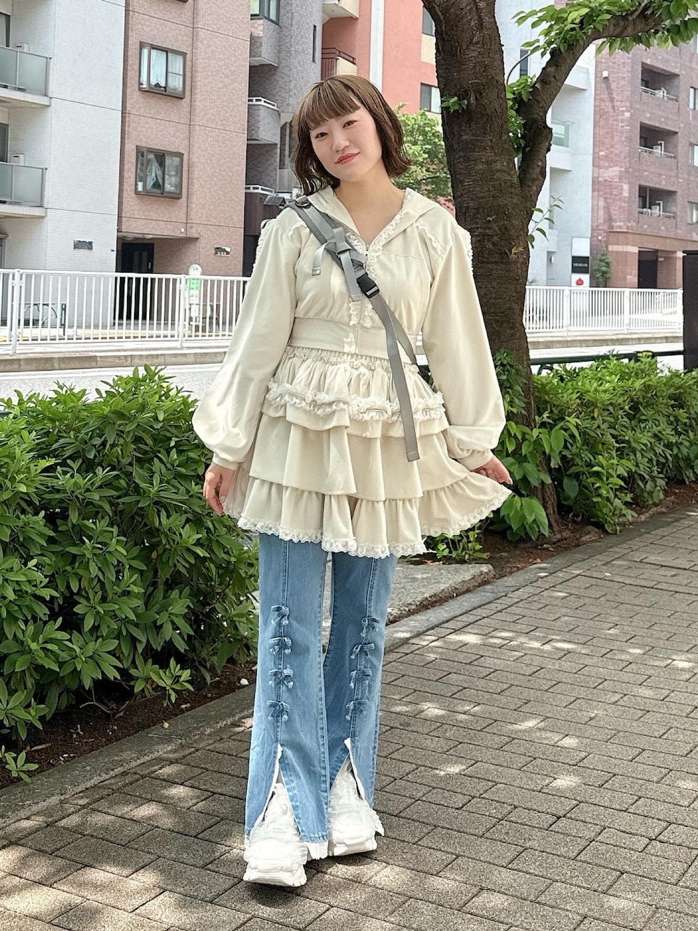 ブルー系のデニムパンツ、ホワイト系のスカート、ホワイト系のパーカーを着用したレディースの春コーディネートの1枚目の写真