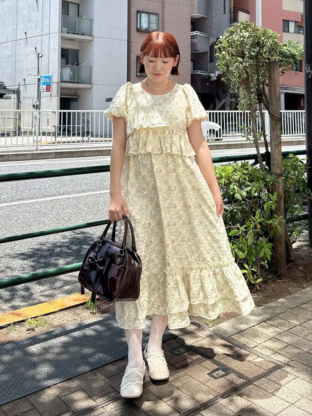 ブラウン系のハンドバッグ、イエロー系のワンピース、ホワイト系のバレエシューズを着用したレディースの春コーディネートの1枚目の写真