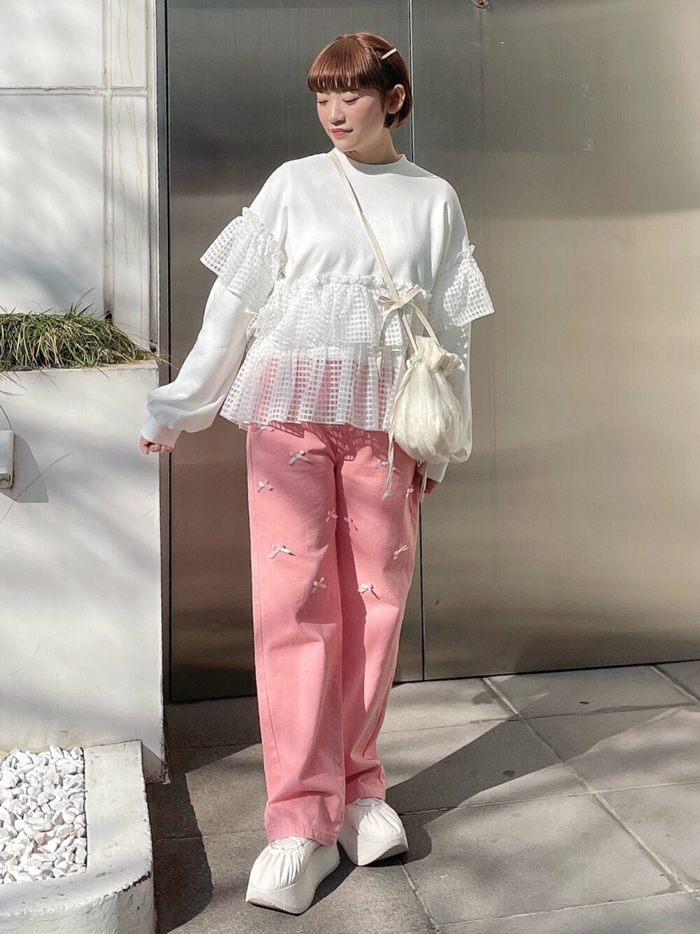 ホワイト系のスウェット、ピンク系のデニムパンツ、ホワイト系のショルダーバッグを着用したレディースの冬コーディネートの1枚目の写真