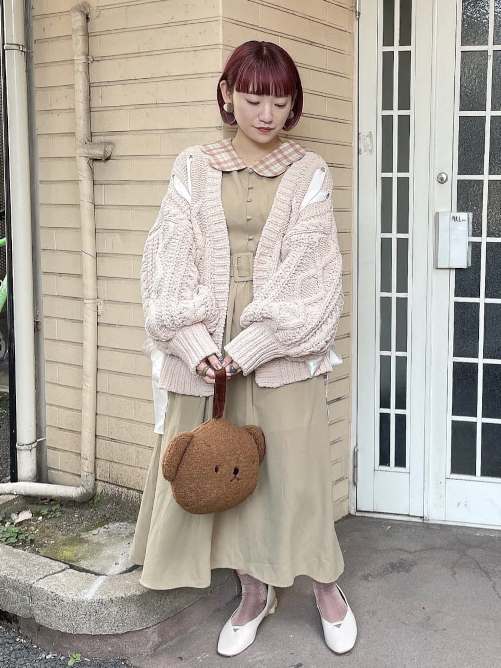 ベージュ系のワンピース、ブラウン系のハンドバッグ、ホワイト系のパンプスを着用したレディースの秋コーディネートの1枚目の写真