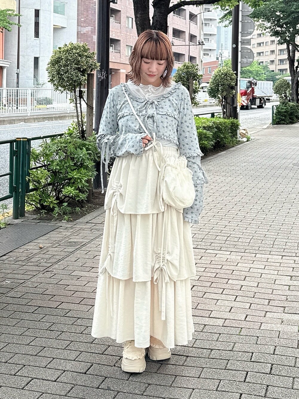 グレー系のカーディガン/ボレロ、ホワイト系のスカート、ホワイト系のショルダーバッグを着用したレディースの夏コーディネートの1枚目の写真