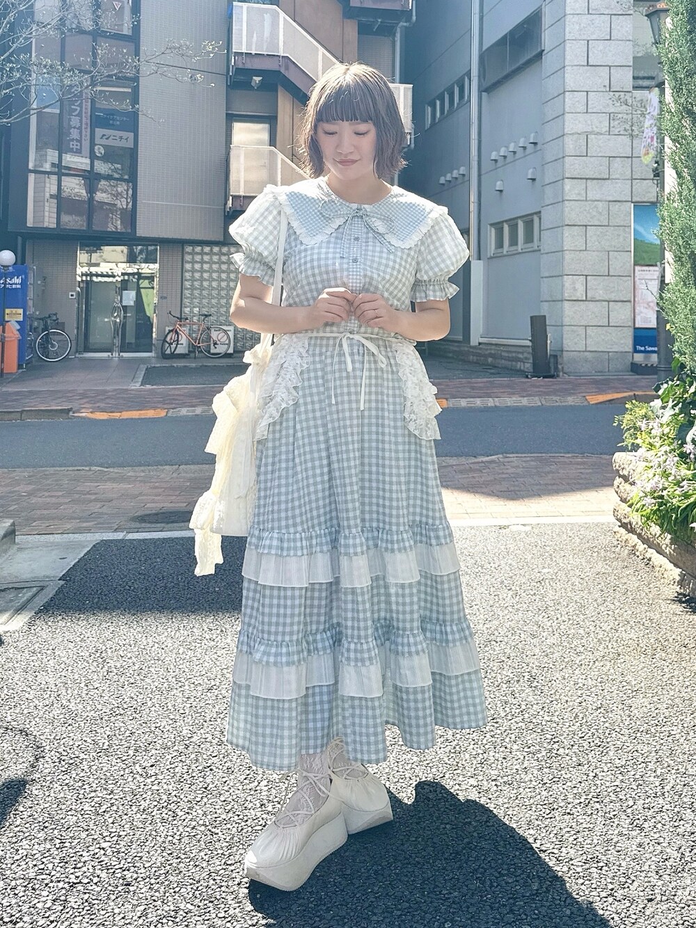 グリーン系のスカート、グリーン系のシャツ/ブラウス、ホワイト系のトートバッグを着用したレディースの春コーディネートの1枚目の写真