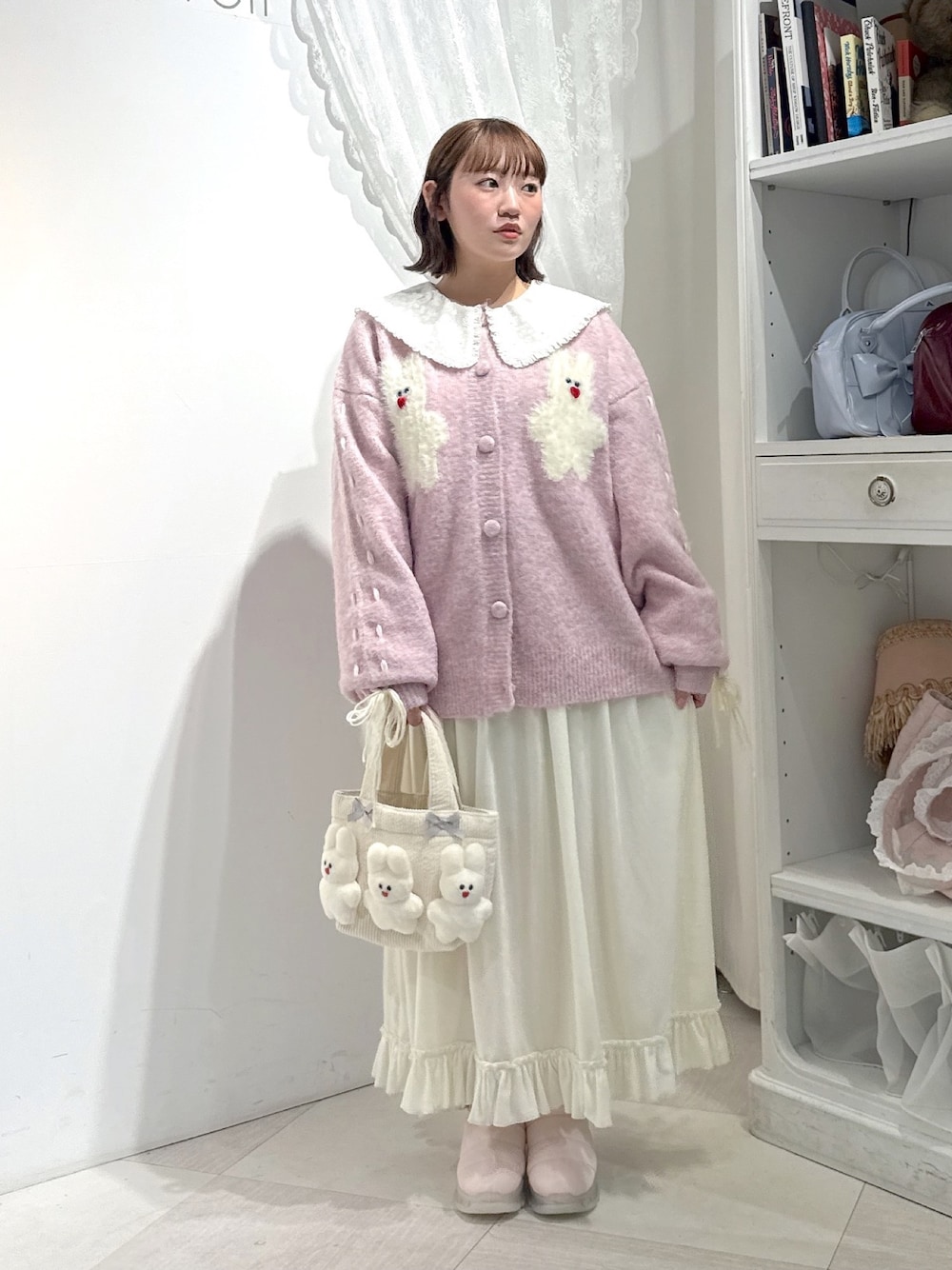 ピンク系のブーツ、ピンク系のカーディガン/ボレロ、ホワイト系のワンピースを着用したレディースの秋コーディネートの1枚目の写真