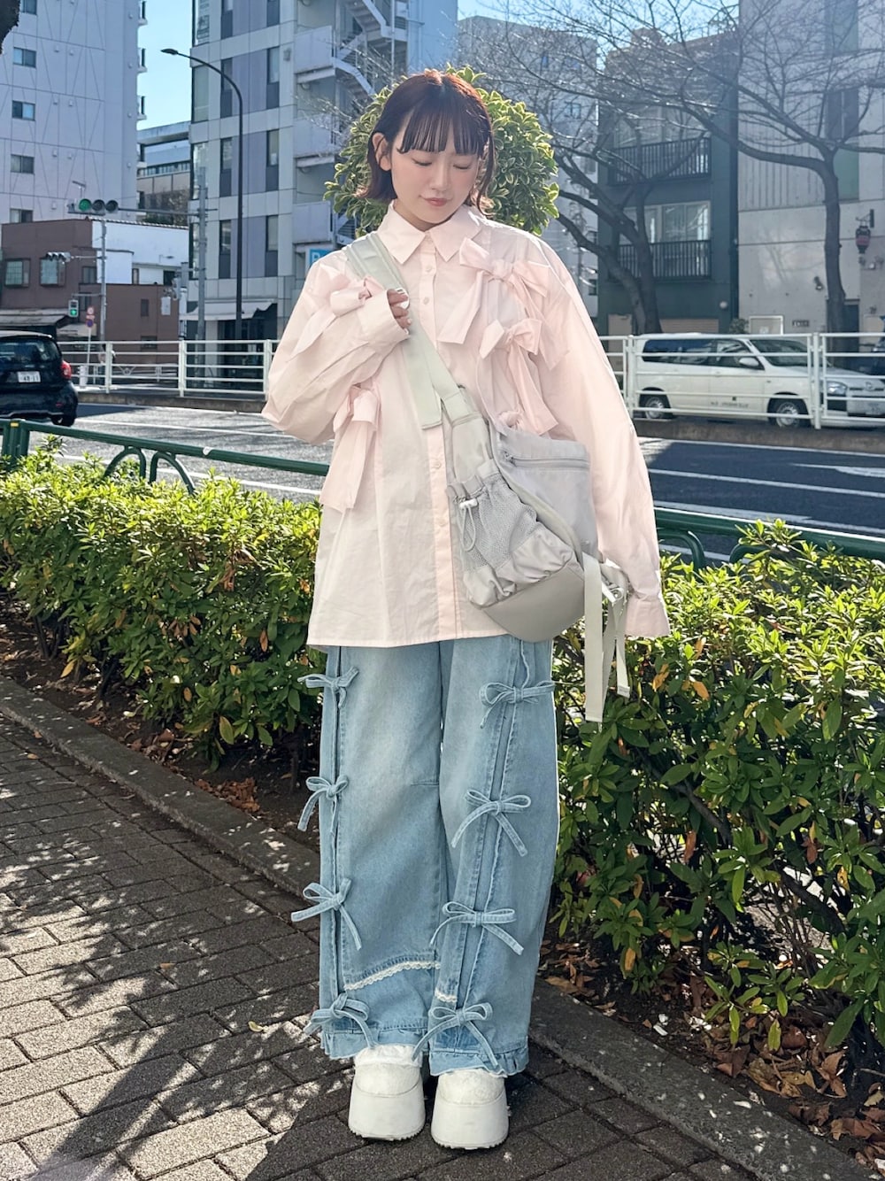 ピンク系のシャツ/ブラウス、グレー系のメッセンジャーバッグ、ブルー系のデニムパンツを着用したレディースの冬コーディネートの1枚目の写真