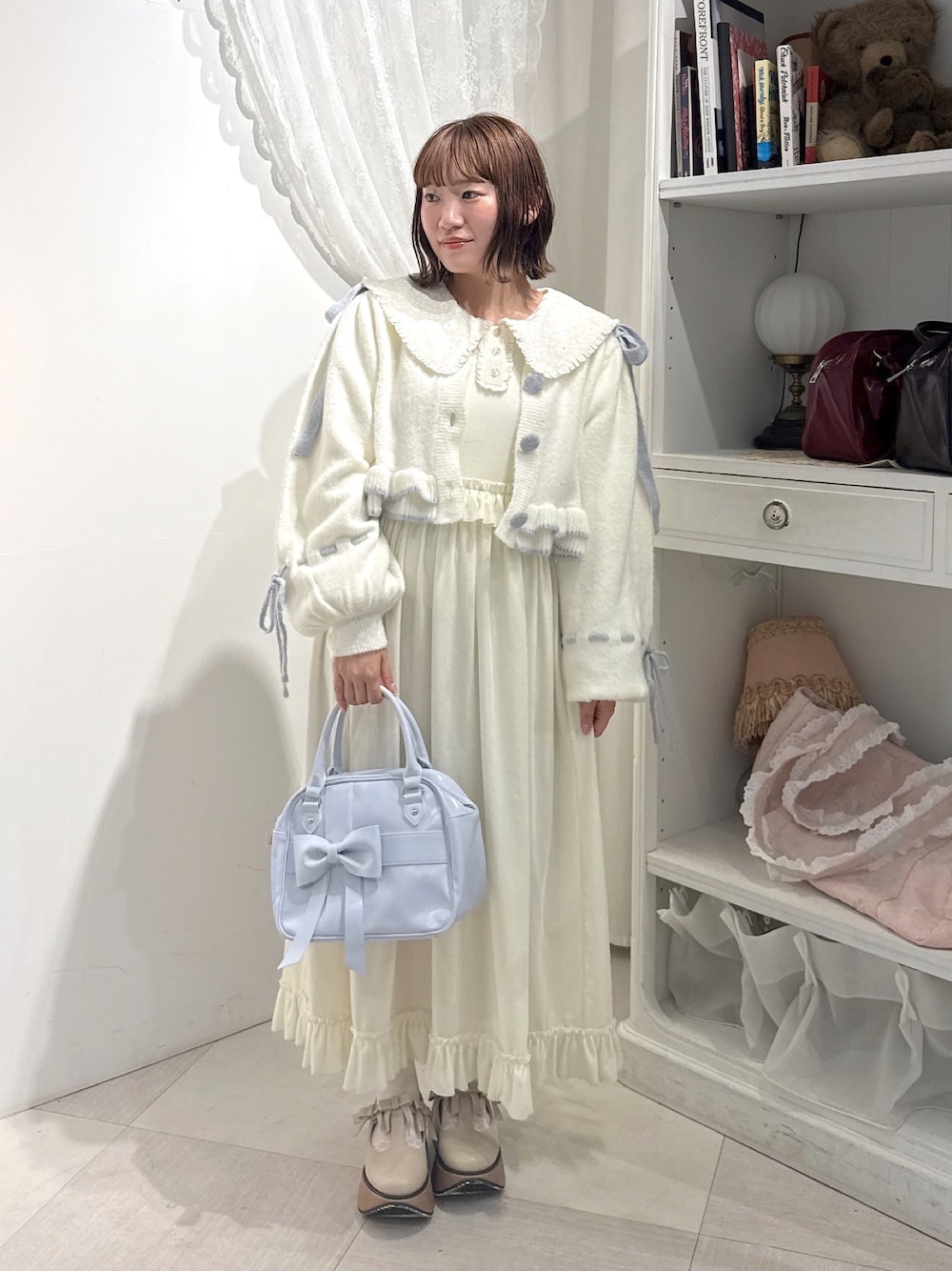 ホワイト系のワンピース、ホワイト系のカーディガン/ボレロ、ブルー系のハンドバッグを着用したレディースの秋コーディネートの1枚目の写真
