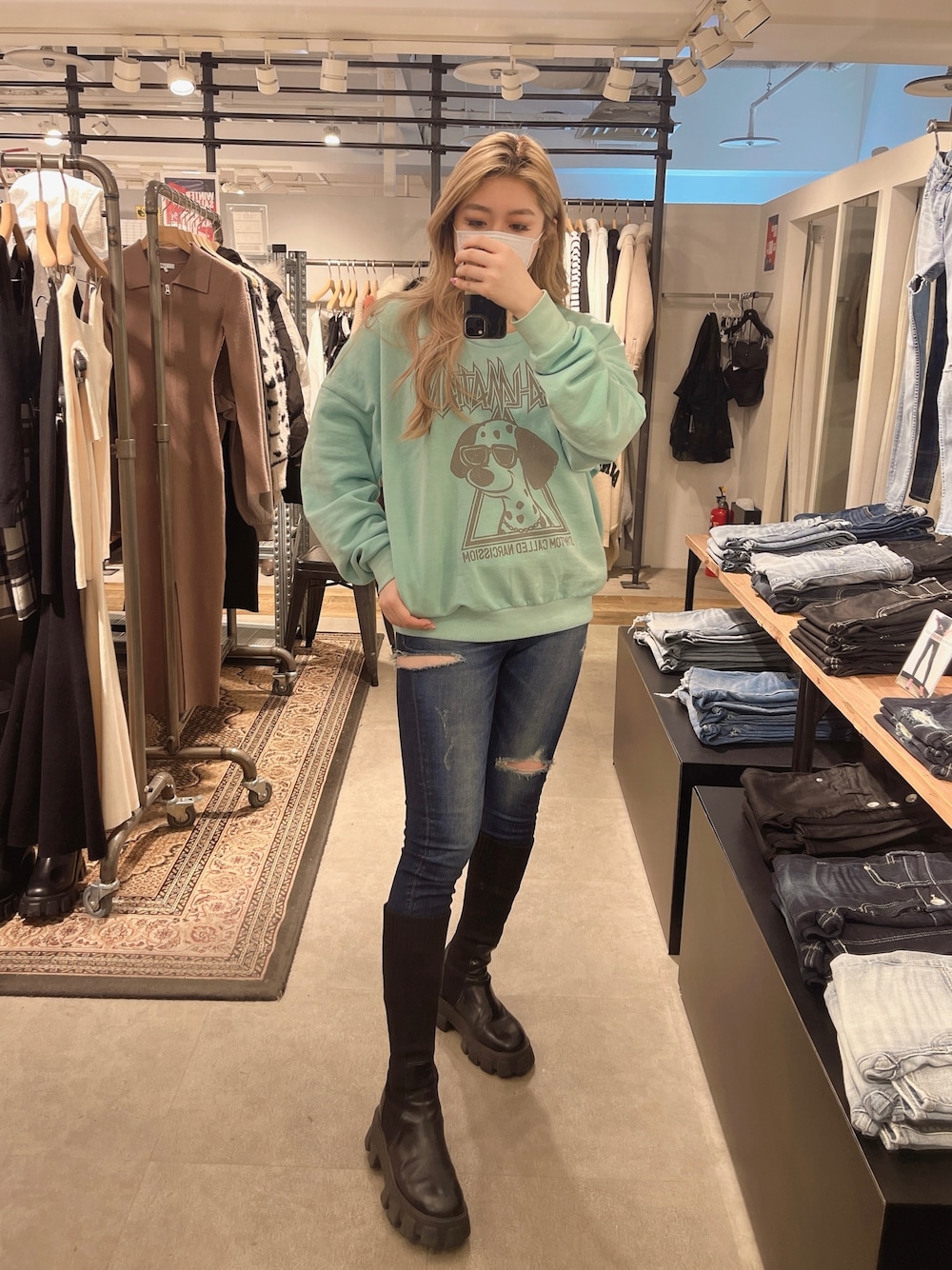 ブルー系のデニムパンツ、ブラック系のブーツ、グリーン系のスウェットを着用したレディースの冬コーディネートの1枚目の写真