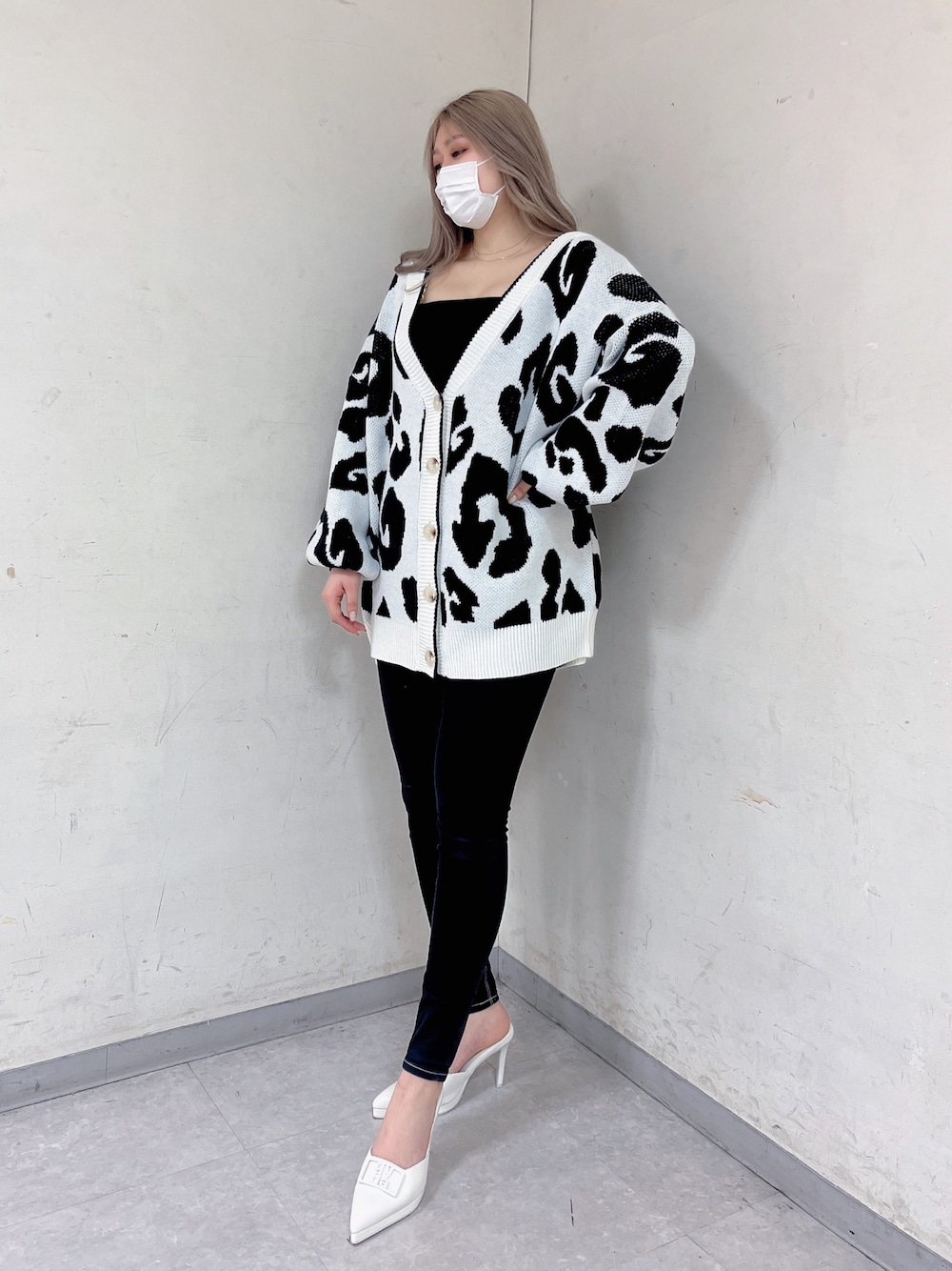 ホワイト系のカーディガン/ボレロ、ブラック系のキャミソール、ブラック系のデニムパンツを着用したレディースの春コーディネートの1枚目の写真