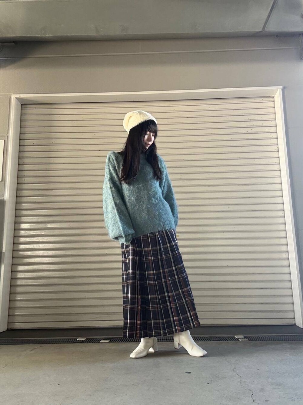 ホワイト系のブーツ、グリーン系のニット/セーター、ブルー系のスカートを着用したレディースの冬コーディネートの1枚目の写真