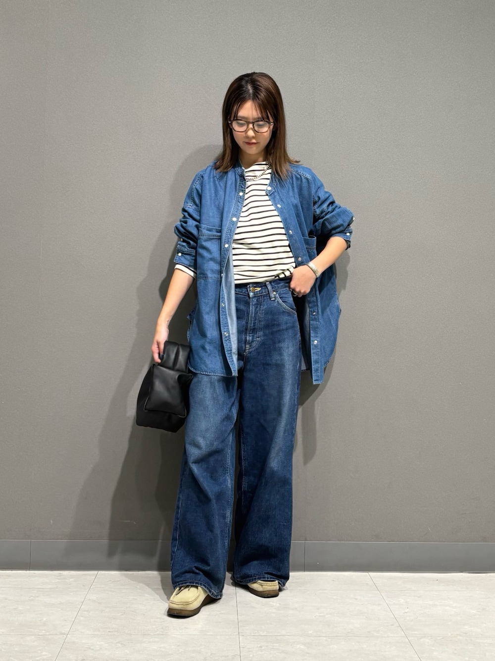 ブルー系のシャツ/ブラウス、ブラック系のTシャツ/カットソー、ブラック系のハンドバッグを着用したレディースの秋コーディネートの1枚目の写真