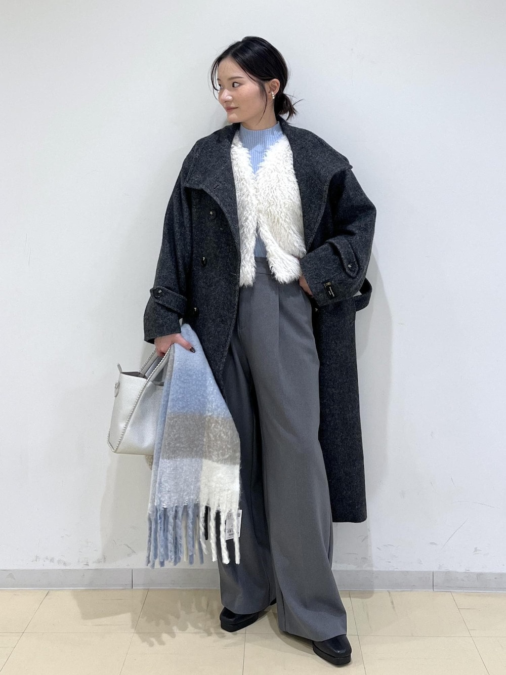 グレー系のスラックス、ホワイト系のベスト、ブルー系のニット/セーターを着用したレディースの秋コーディネートの1枚目の写真