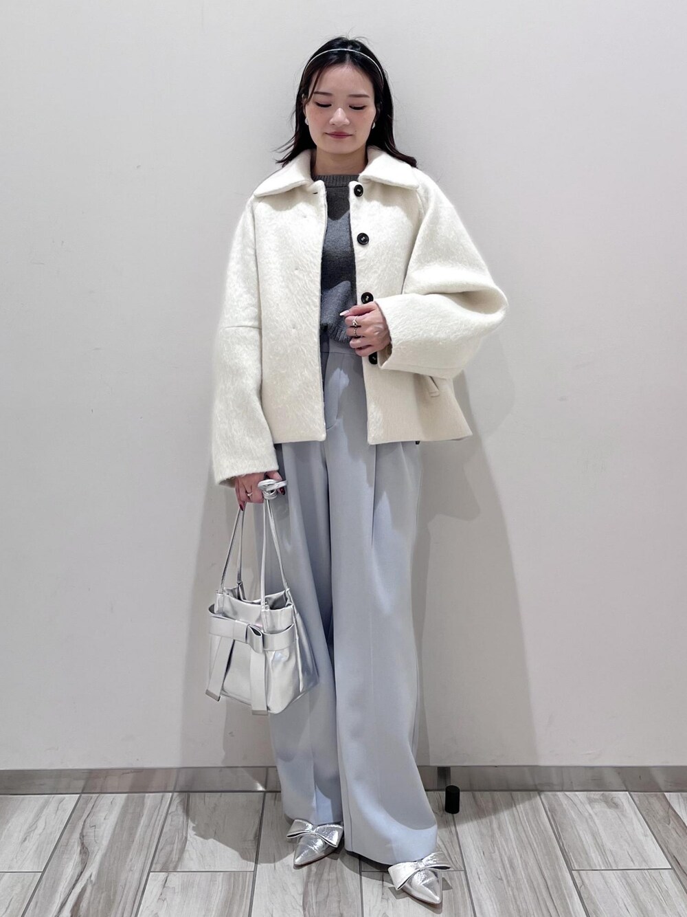 シルバー系のパンプス、シルバー系のショルダーバッグ、ブルー系のスラックスを着用したレディースの秋コーディネートの1枚目の写真