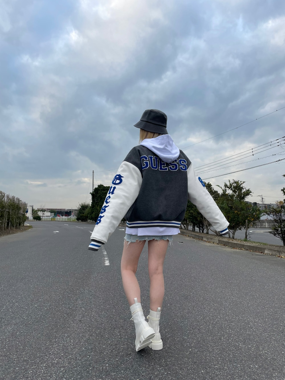 ブラック系のスタジャン、ホワイト系のパーカー、ブラック系のハットを着用したレディースの冬コーディネートの1枚目の写真