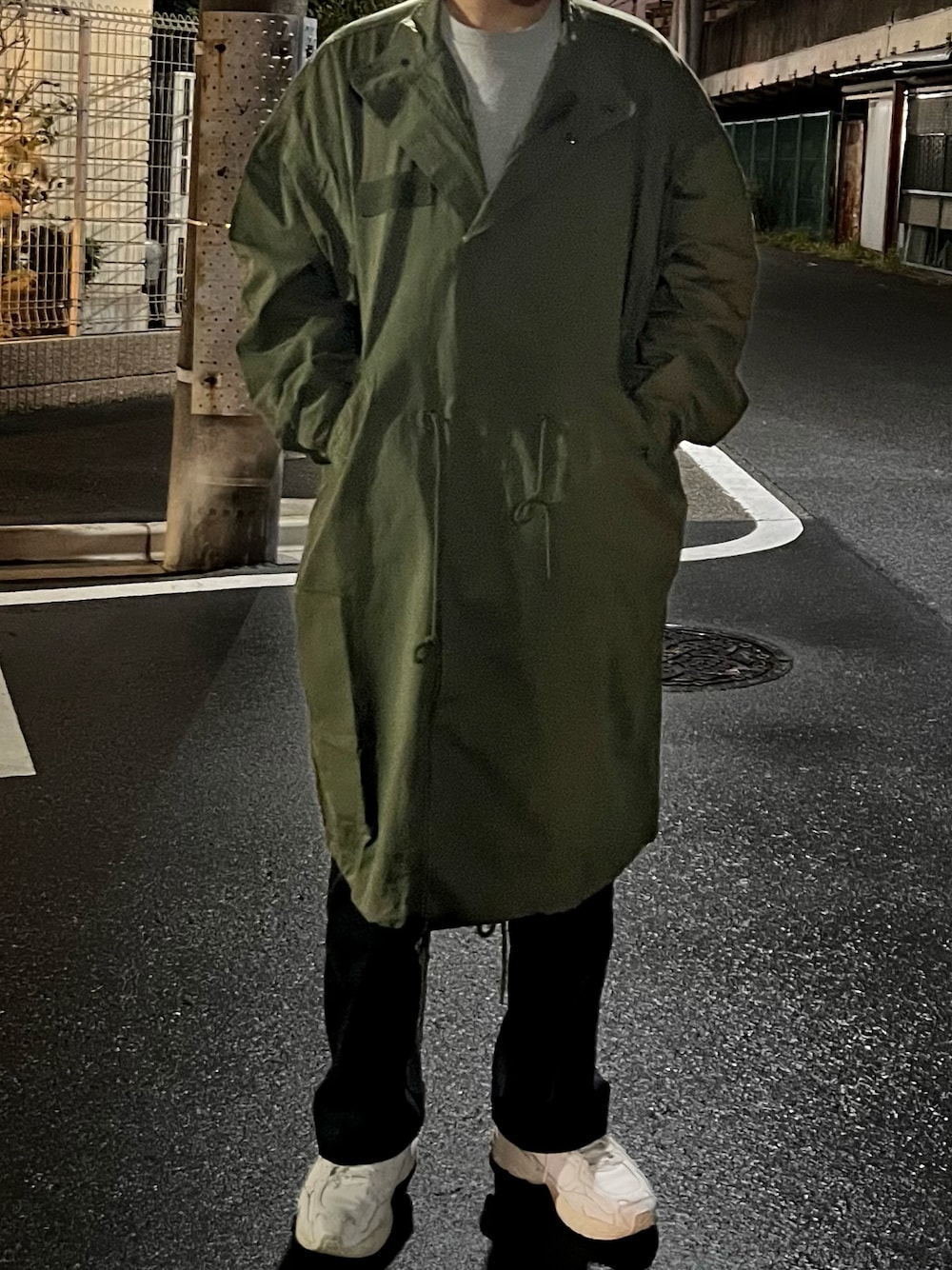 ブラック系のデニムパンツ、ホワイト系のスニーカー、グリーン系のジャケット/アウターを着用したメンズの秋コーディネートの1枚目の写真