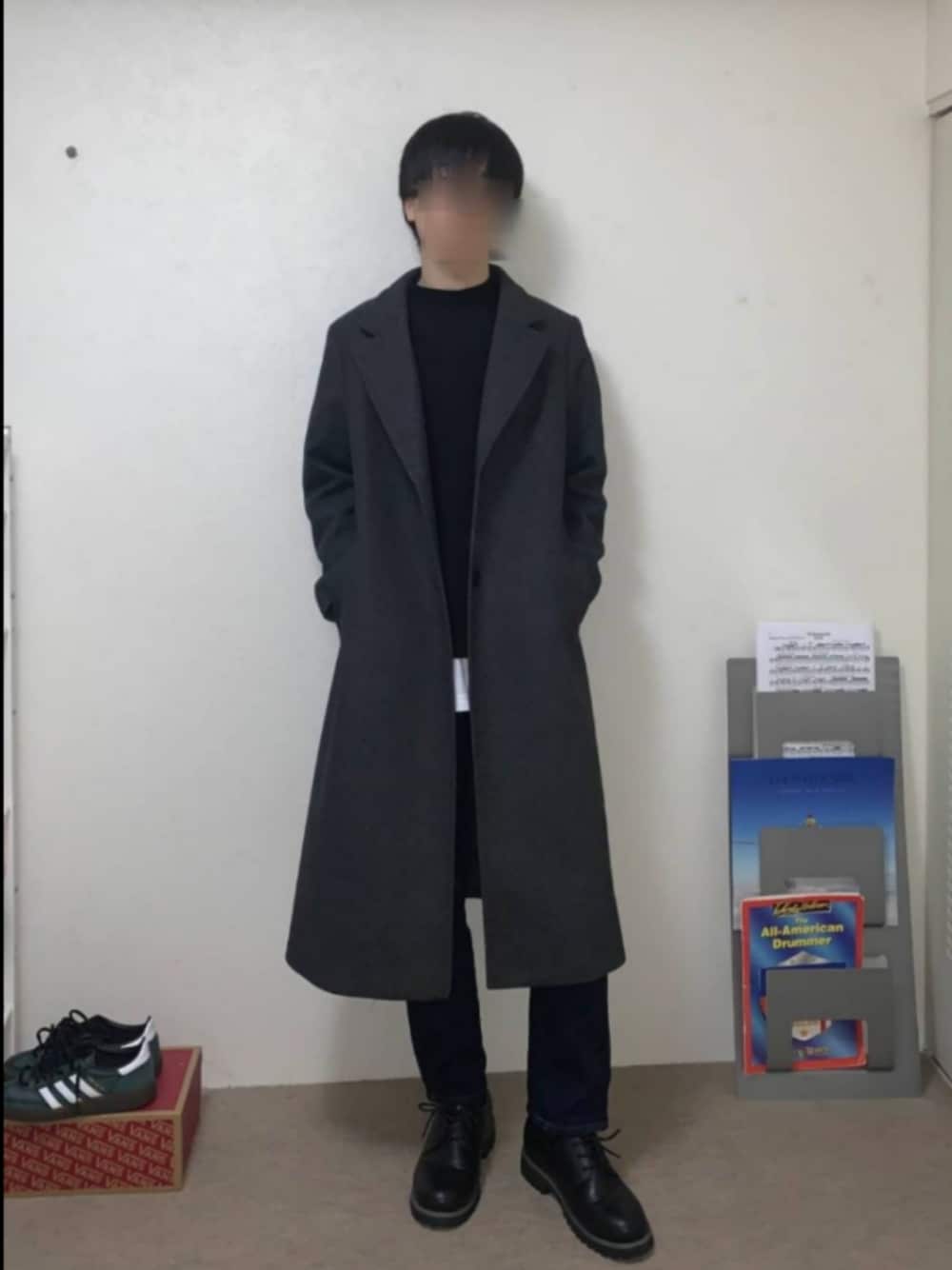 グレー系のチェスターコート、ブラック系のTシャツ/カットソー、ブルー系のデニムパンツを着用したメンズの冬コーディネートの1枚目の写真