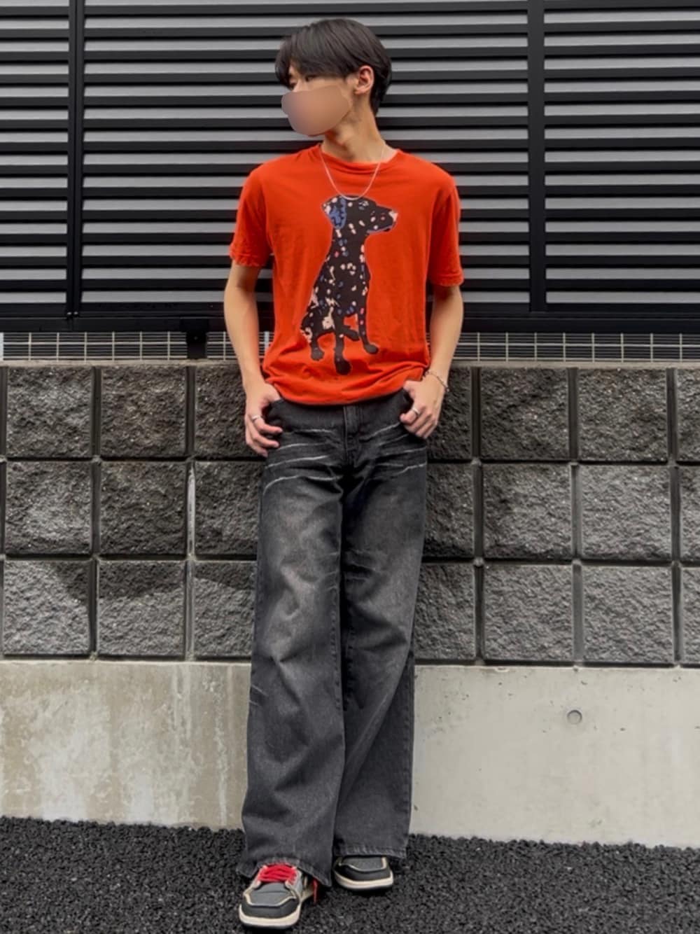 ブラック系のデニムパンツ、オレンジ系のTシャツ/カットソー、ブラック系のスニーカーを着用したメンズの夏コーディネートの1枚目の写真