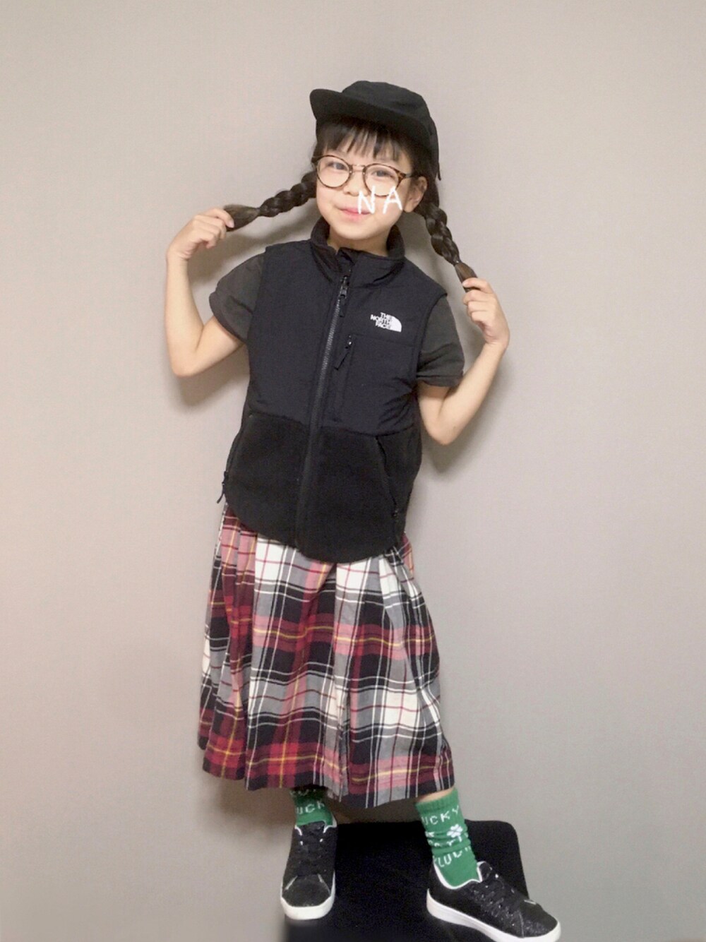 ブラック系のベスト、レッド系のスカート、ブラック系のスニーカーを着用したキッズの秋コーディネートの1枚目の写真