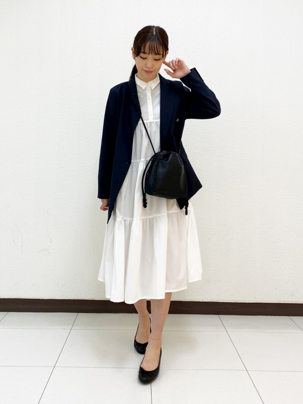 ホワイト系のシャツワンピース、ブラック系のショルダーバッグ、ブラック系のテーラードジャケットを着用したレディースの冬コーディネートの1枚目の写真