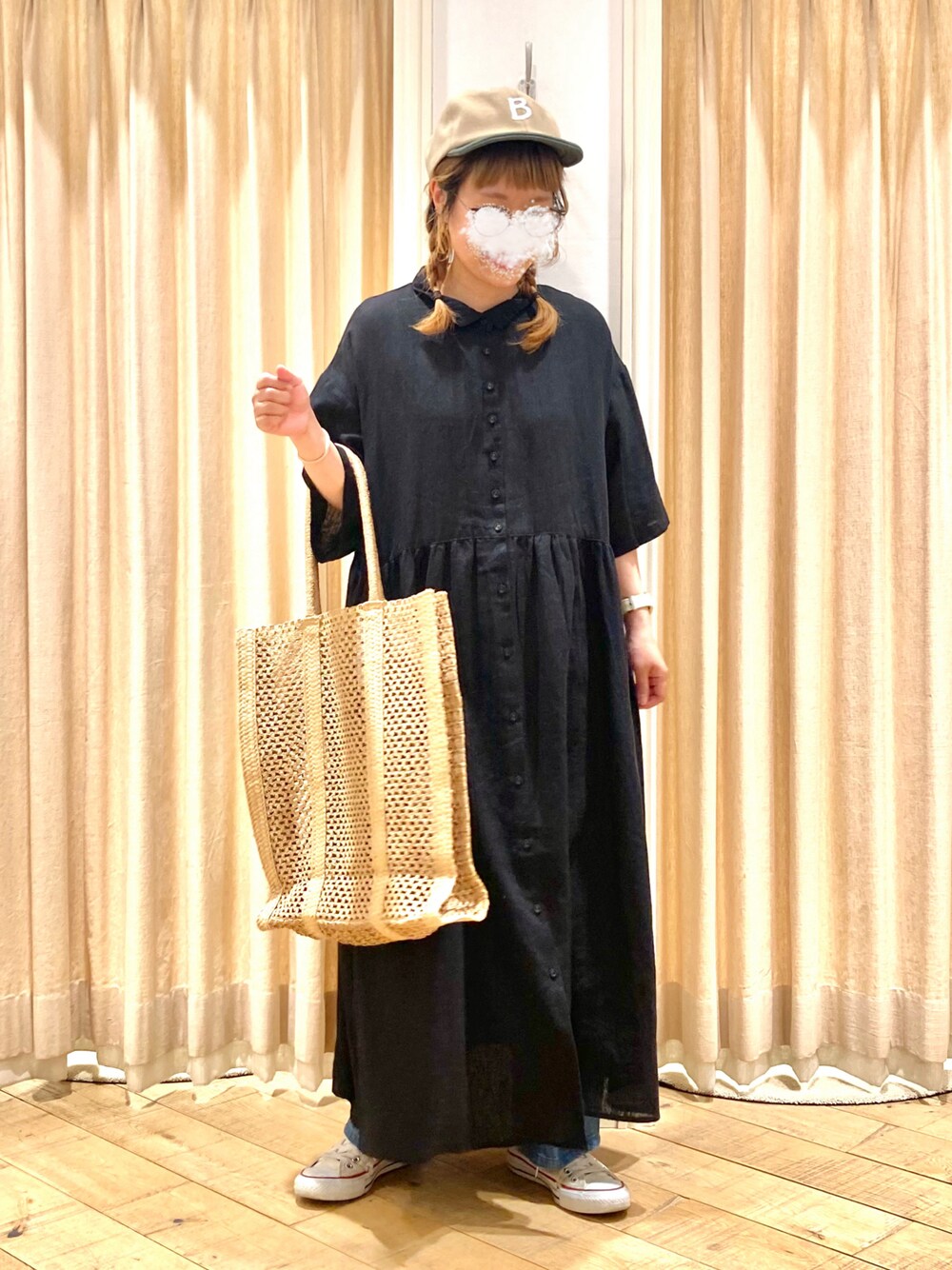 ブラック系のワンピース、ブルー系のデニムパンツ、ベージュ系のハンドバッグを着用したレディースの春コーディネートの1枚目の写真